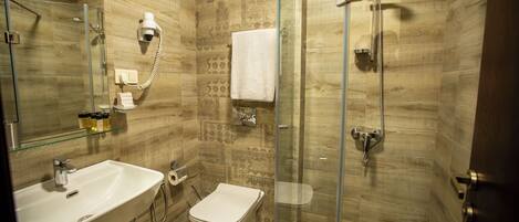 A modern bathroom with a glass-enclosed shower, a white sink, and a toilet.