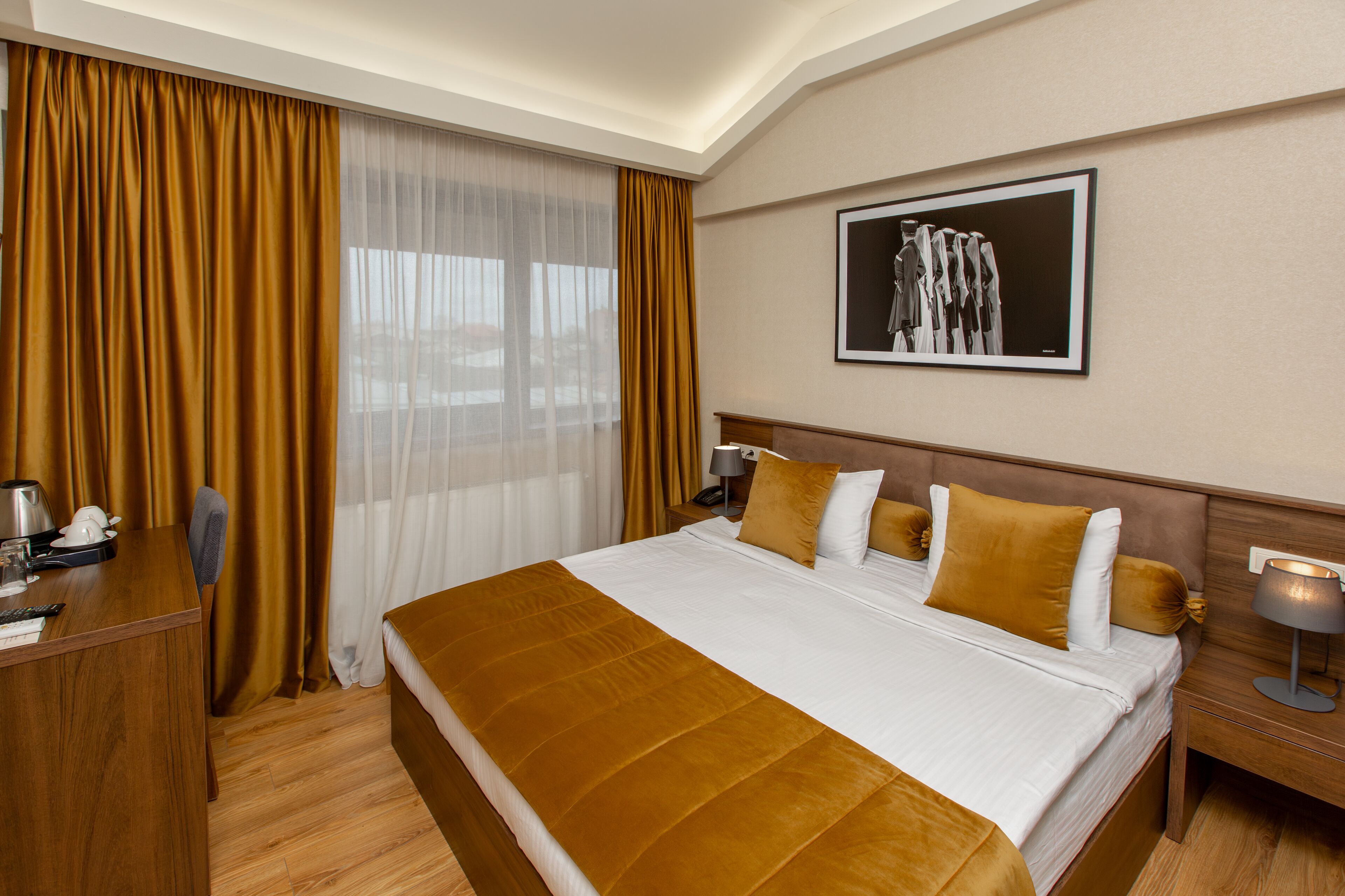 Une chambre d’hôtel avec un grand lit, un bureau, une chaise, une table de chevet avec une lampe et un tableau encadré au mur.