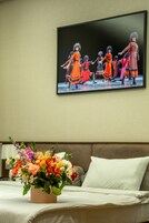 A bedroom with a bed, a floral arrangement on the bed, and a painting on the wall.
