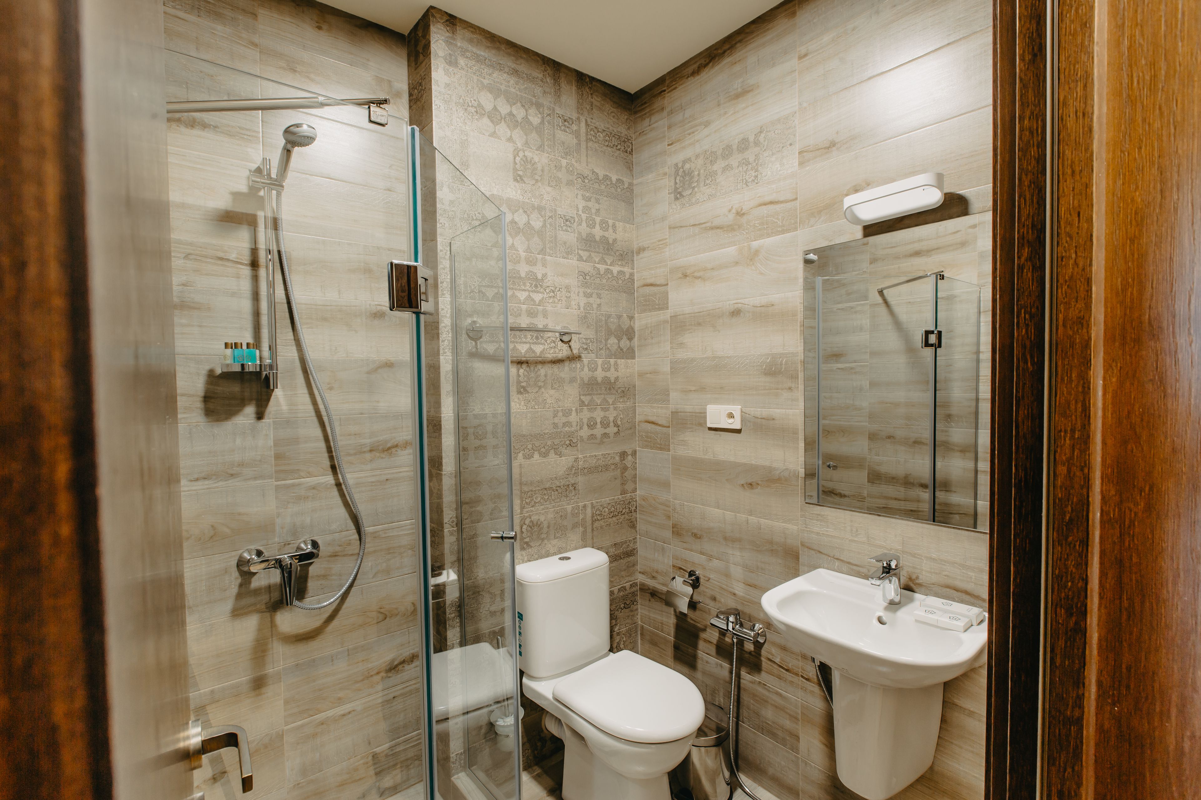 Un baño moderno con ducha de mampara de vidrio, inodoro y lavamanos.
