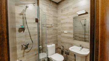 Un baño moderno con ducha de mampara de vidrio, inodoro y lavamanos.