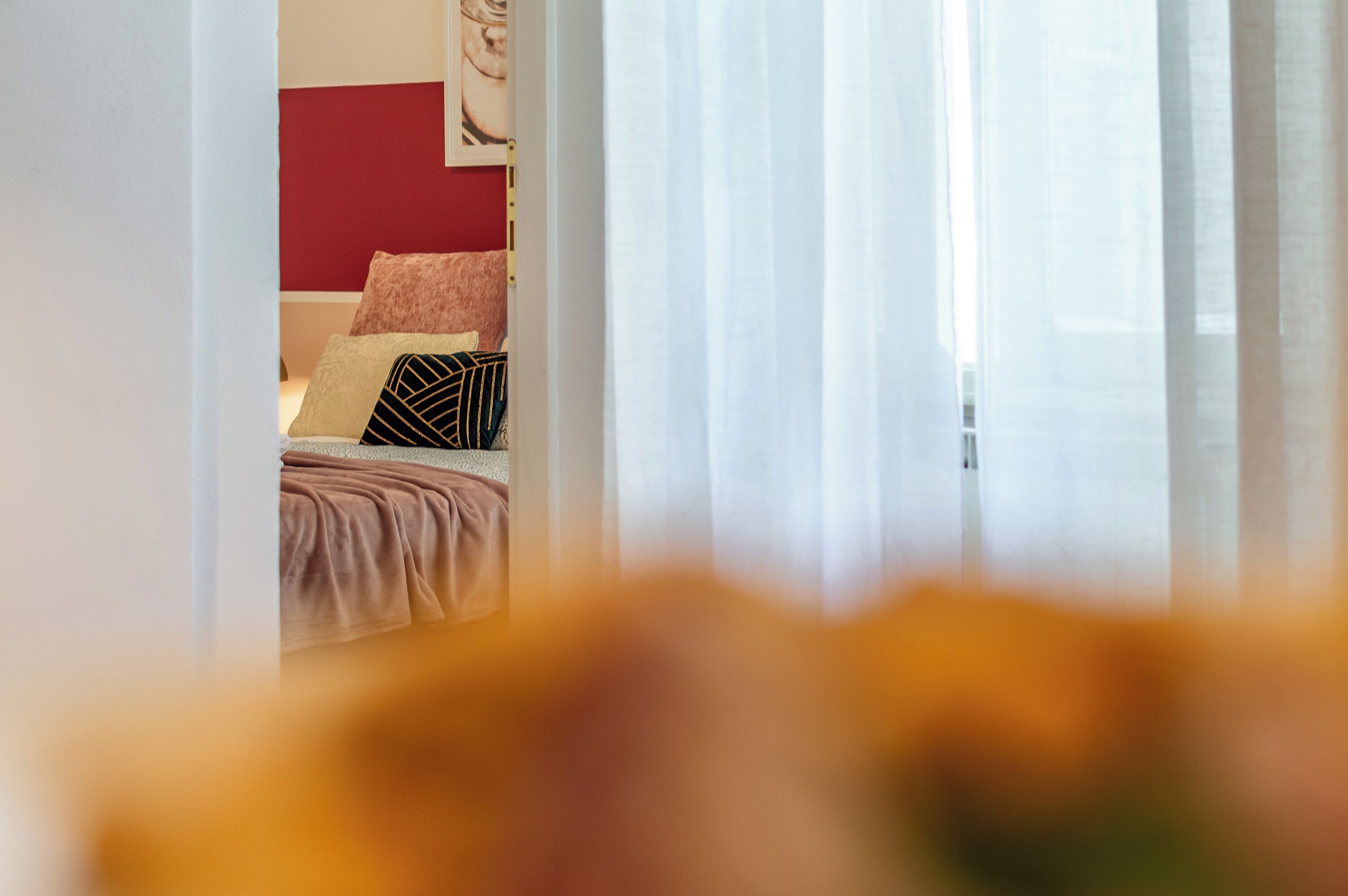 A bedroom with a bed, pillows, and a red accent wall.