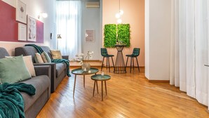 A modern living room with a grey sofa, green cushions, a glass coffee table, and a green wall with a vertical garden. - Wine Apartments Florence Moscato (Florence)