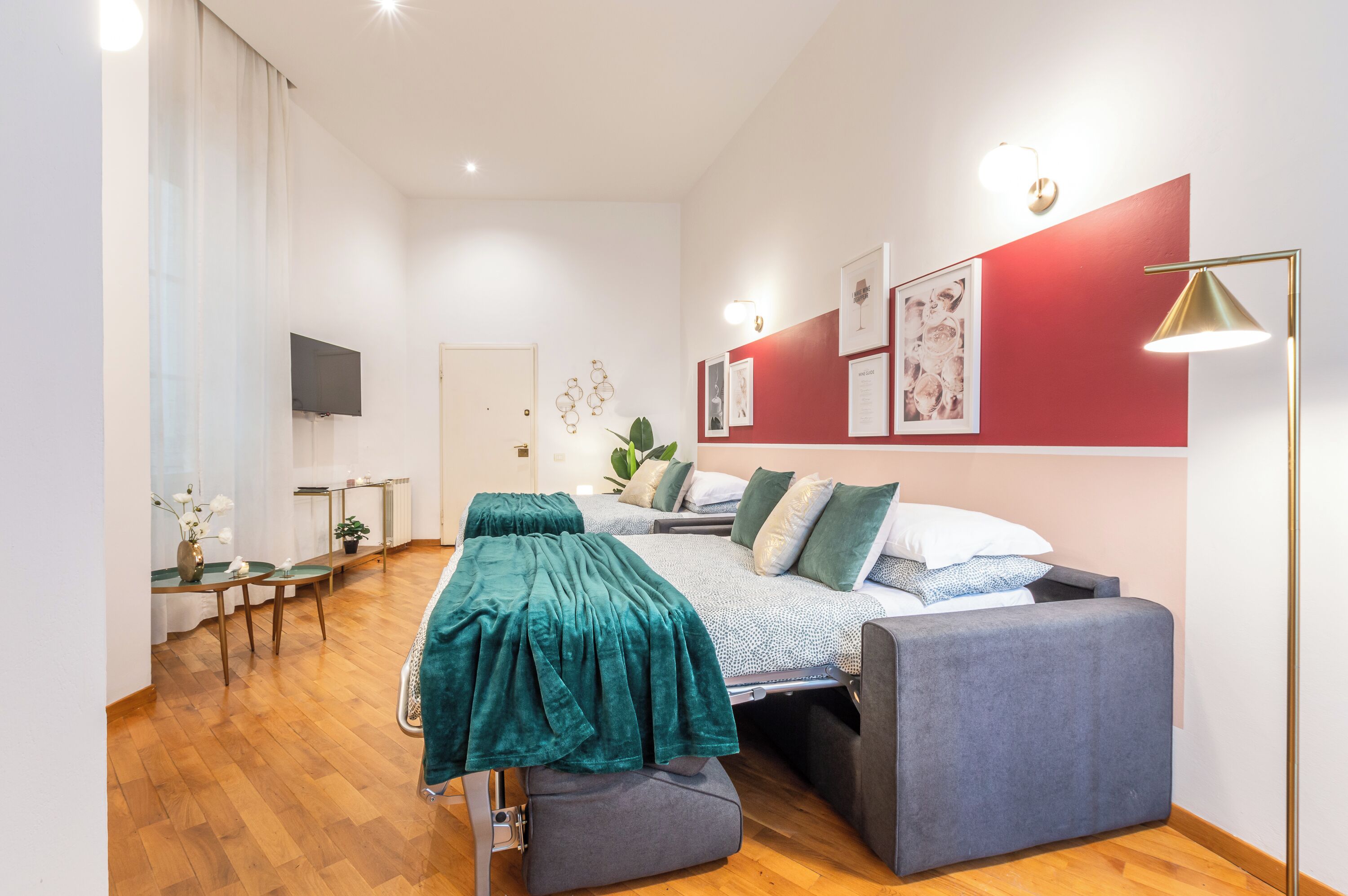 Een moderne slaapkamer met een bed, nachtkastjes, een televisie en kunst aan de muur.