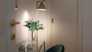 A room with a glass table, a vase with flowers, a green chair, and a floor lamp. - Wine Apartments Florence Moscato (Florence)