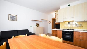 Une cuisine moderne avec des meubles en bois, un poêle noir et un coin repas comprenant une table et des chaises en bois.