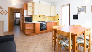 Une cuisine compacte avec des meubles en bois, un four encastré et un coin repas comprenant une table et des chaises.