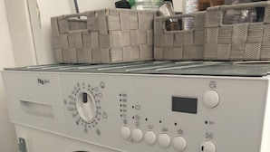 A front view of a front-loading washing machine with a control panel, a small storage basket on top, and a control panel with various buttons and a dial. - 2 Zimmer Wohnung in Ludwigsburg Mitte (Ludwigsburg)