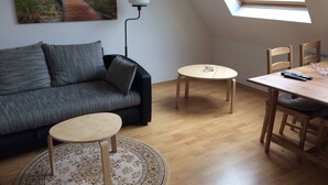 A cozy living room with a sofa, a small round table, a dining table with chairs, a lamp, and a painting on the wall. - 2 Zimmer Wohnung in Ludwigsburg Mitte (Ludwigsburg)
