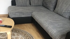 A modern living room with a grey sectional sofa, a small wooden coffee table, and a patterned rug. - 2 Zimmer Wohnung in Ludwigsburg Mitte (Ludwigsburg)