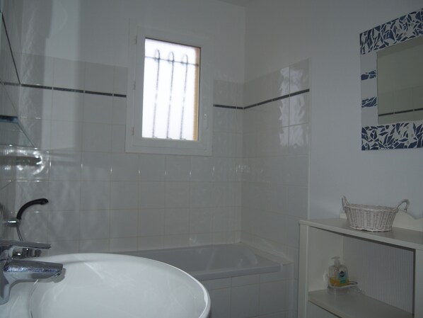 Une salle de bain avec une baignoire, une fenêtre, un miroir et un lavabo.