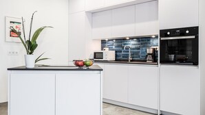 Ett modernt kök med vita skåp, en svart bänkskiva, en mikrovågsugn, en kaffebryggare och en ugn från Whirlpool.