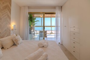A hotel room with a bed, a desk, and a view of the beach.