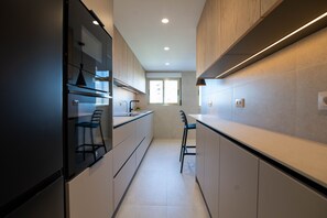 A narrow kitchen with modern appliances, a window, and a bar area.