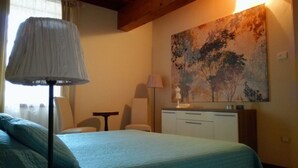 Une chambre à coucher avec un lit, un bureau, une chaise, une lampe et un tableau au mur.