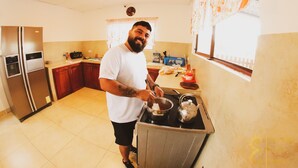 A kitchen with a stove, refrigerator, and wooden cabinets. - Casa Hospedaje Punta Arena (Puerto Villamil)