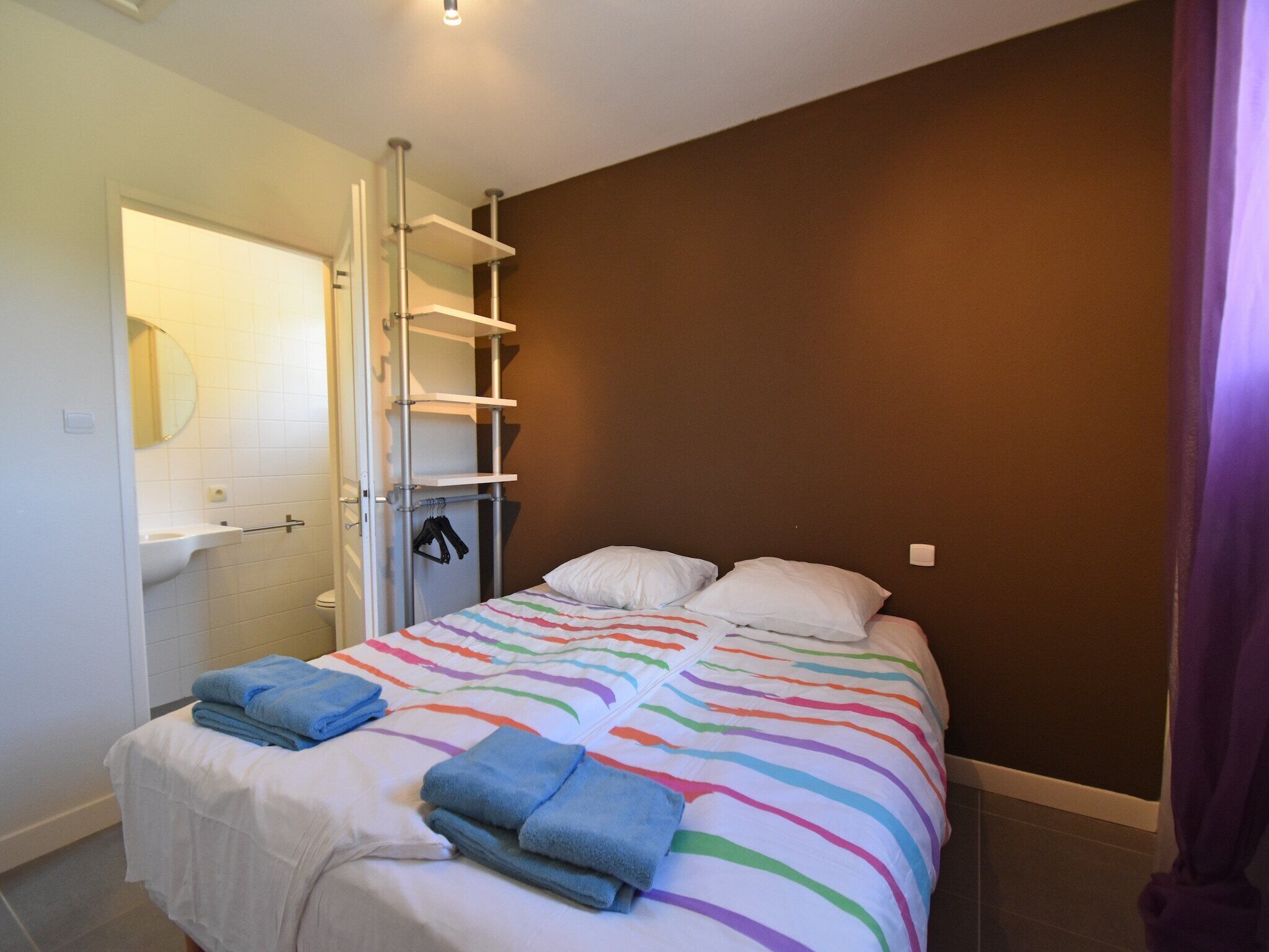 Ein Schlafzimmer mit Bett, Schrank, Spiegel und Bad.
