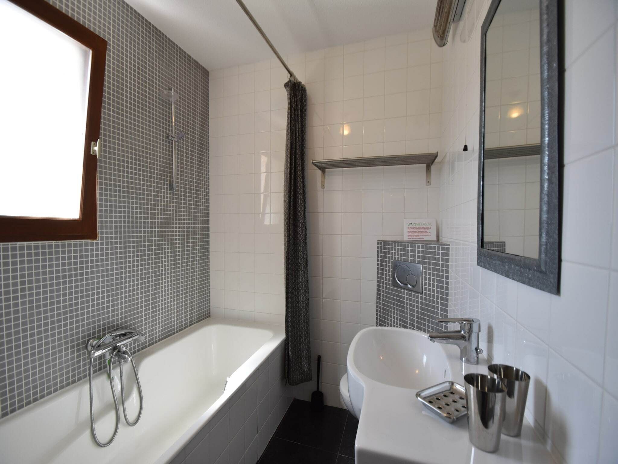 Une salle de bain avec une baignoire, un lavabo, un miroir et un rideau de douche.