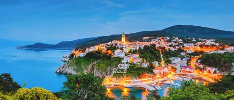A coastal town with a prominent tower, a marina, and buildings on a hillside.