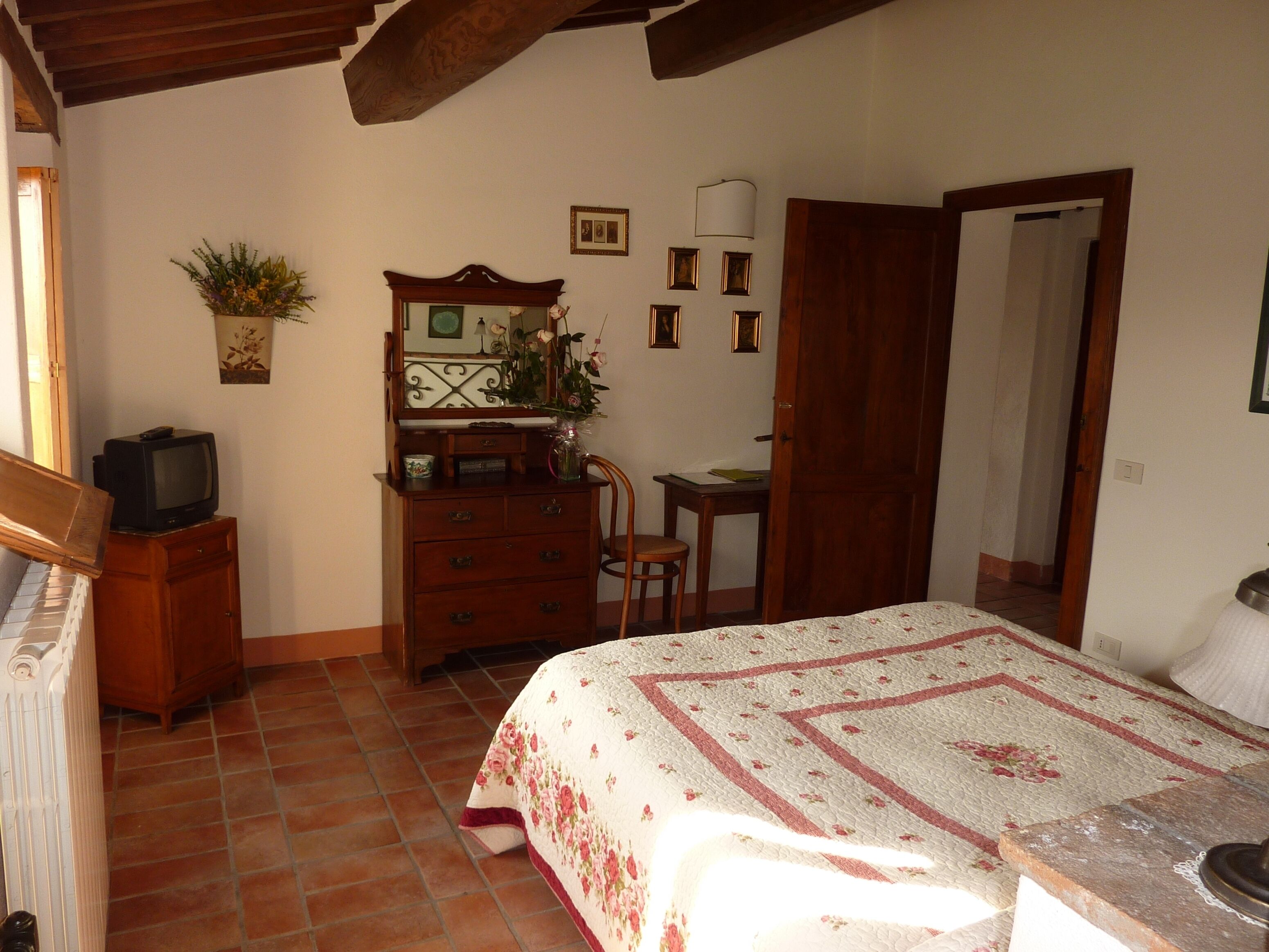 Une chambre à coucher comprenant un lit, une commode, un téléviseur et un bureau avec une chaise.