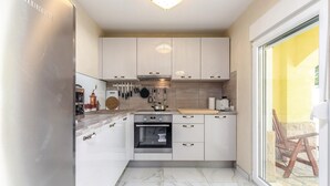 A compact kitchen with white cabinets, a built-in oven, and a large window. - Luxurious home in Bribir (Bribir)
