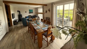 Amplia sala de estar con mesa de comedor, sofás y un gran ventanal con vistas al exterior.