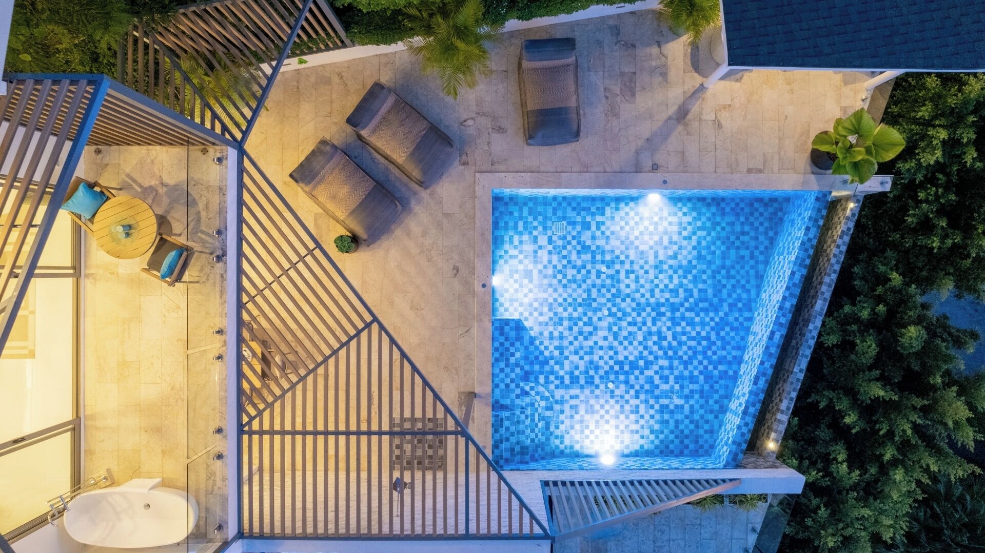 A rooftop pool with a tiled floor, surrounded by a wooden deck and a staircase.
