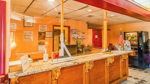 A reception area with a counter, a cash register, a vending machine, and a flag. - Castle Inn & Suites by OYO Lawton (Lawton)