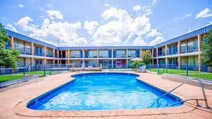 A hotel with a central swimming pool, multiple balconies, and a clear blue sky. - Castle Inn & Suites by OYO Lawton (Lawton)