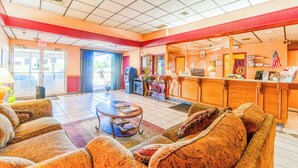 A lobby with patterned sofas, a reception desk, and an exit door. - Castle Inn & Suites by OYO Lawton (Lawton)