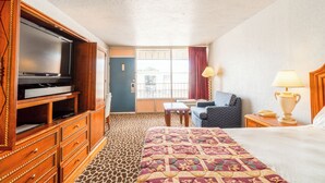 A hotel room with a bed, a television, a desk, a chair, and a window with curtains. - Castle Inn & Suites by OYO Lawton (Lawton)