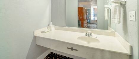 A bathroom with a white sink, a mirror, and a towel rack.