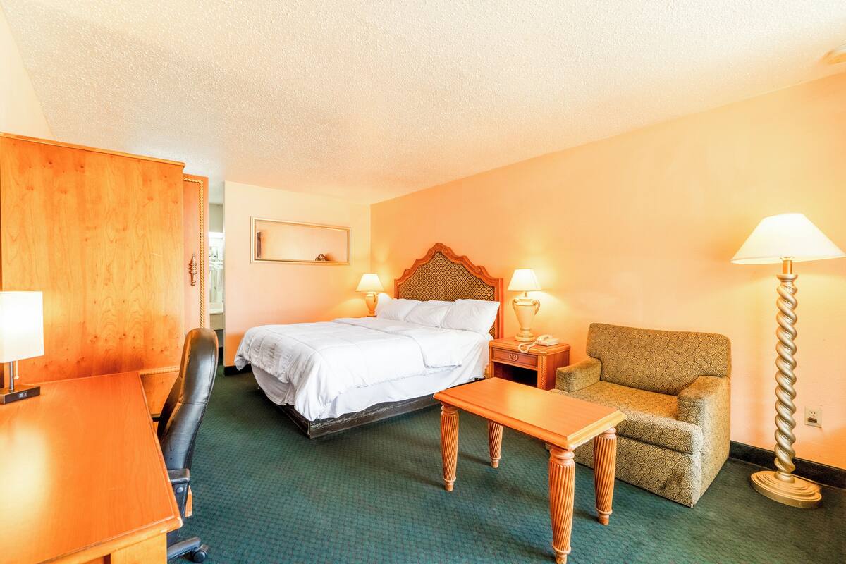 Una habitación de hotel con cama, escritorio, silla, mesa y lámpara.