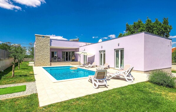 A modern house with a swimming pool, outdoor seating, and a stone wall. - Luxurious home in Marici with sauna (Marici)