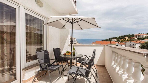 Ein Balkon mit Tisch, Stühlen und Sonnenschirm.