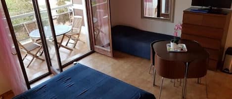 Een slaapkamer met een bed, bureau, stoel, kapstok en een televisie.