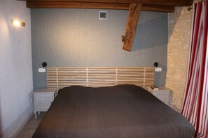 Une chambre à coucher avec une tête de lit en bois, un lit, deux tables de chevet et une petite table d’appoint.