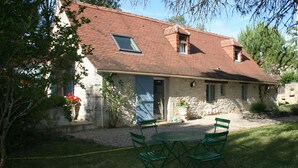 A stone house with a tiled roof, a small window, and a door. There is a green table and chairs in the front yard. - Former sheepfold renovated, quiet, with heated pool. (Montgesty)