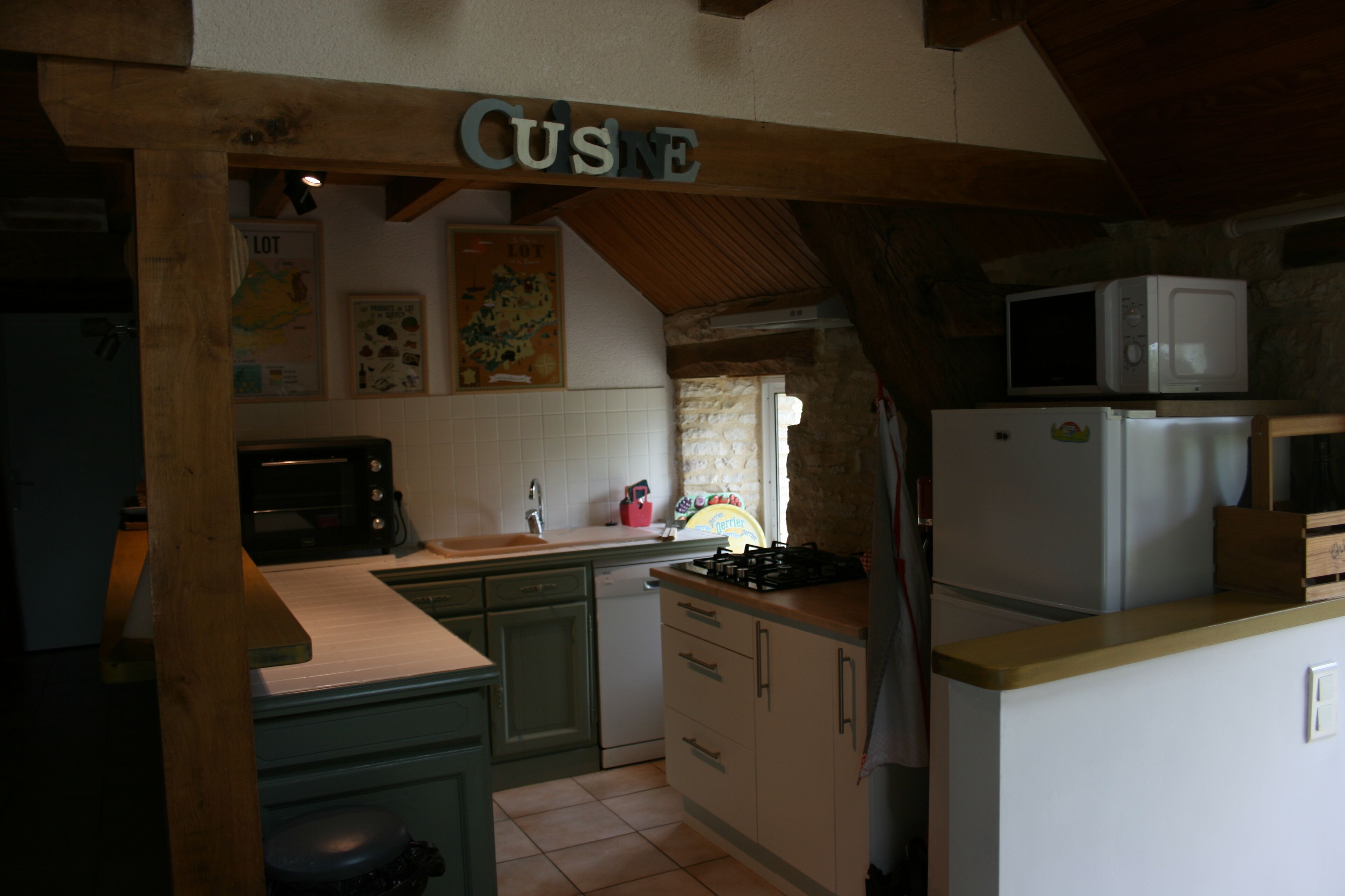 Cucina con travi in legno, forno a microonde, frigorifero e fornello.