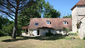 A stone house with a tiled roof, a covered porch, and a small garden area. - Former sheepfold renovated, quiet, with heated pool. (Montgesty)