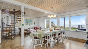 Un comedor amplio con vistas al mar, una escalera de madera y un ventanal grande.