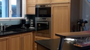 A modern kitchen with wooden cabinets, a built-in oven, and a stainless steel refrigerator. - House exceptional sea view on the Pink Granite Coast (Penvénan)