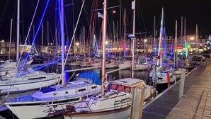 A marina at night with multiple boats docked, illuminated by blue and red lights. - House exceptional sea view on the Pink Granite Coast (Penvénan)