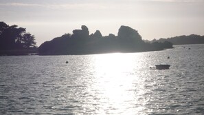 Un plan d’eau calme, avec une petite île qui se profile à l’horizon.
