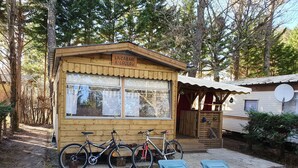 Een houten hutje met een bord waarop 'LA CABANE A LOULOU' staat en twee fietsen ervoor geparkeerd.