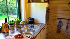 Ett kök med en diskho i rostfritt stål, en bänkskiva i trä och ett fönster med utsikt över grönområden.