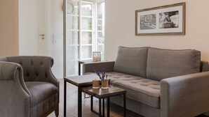 A living room with a grey sofa, a tufted armchair, and a wooden coffee table with vases. - Apartment 12 - Edersee time out (Edertal)