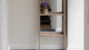 A hallway with a wooden shelf holding a vase of purple flowers, a mirror, and a wall-mounted light fixture. - Apartment 12 - Edersee time out (Edertal)