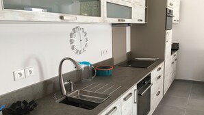 A modern kitchen with a stainless steel sink, a clock, and a built-in oven.