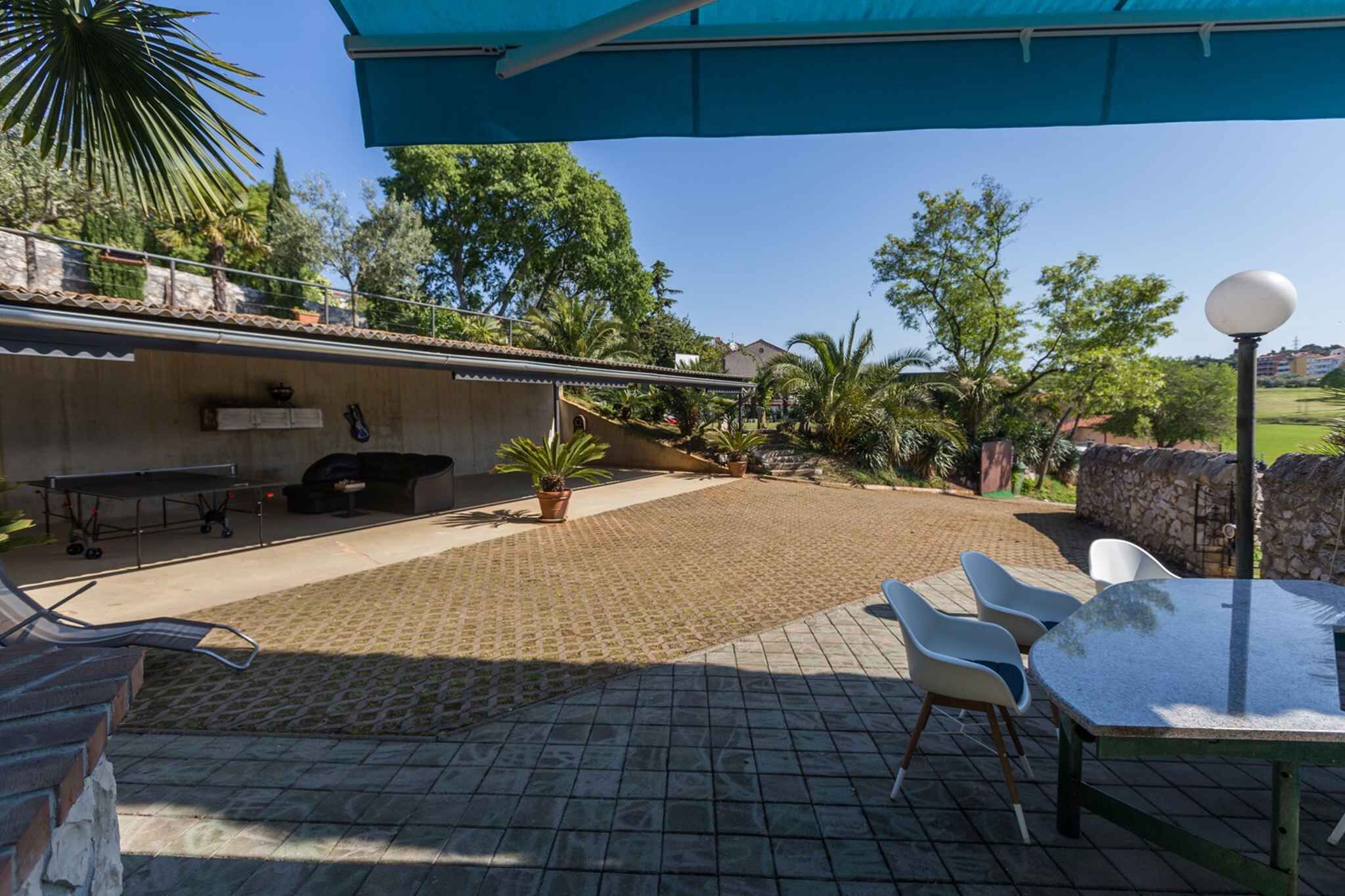 An outdoor patio area with a table and chairs, a barbecue grill, and potted plants.